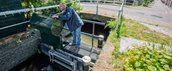 Man staat bij stuw op een gracht in een stadscentrum