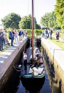 Het schutten van de sluis. Het waterpeil zakt en daardoor kan de boot van de boezem naar de lager gelegen polder varen.