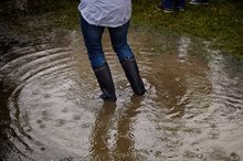 Persoon met hoge laarzen in een grote plas met water.