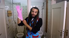 Man met rubberen handschoen die toilet onderhoudt